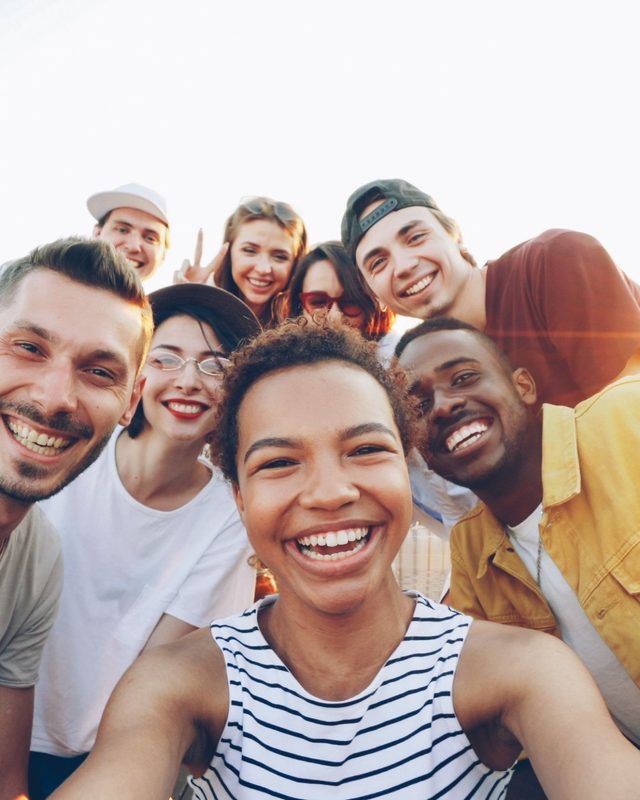 Friends crowding into a rooftop selfie at sunset